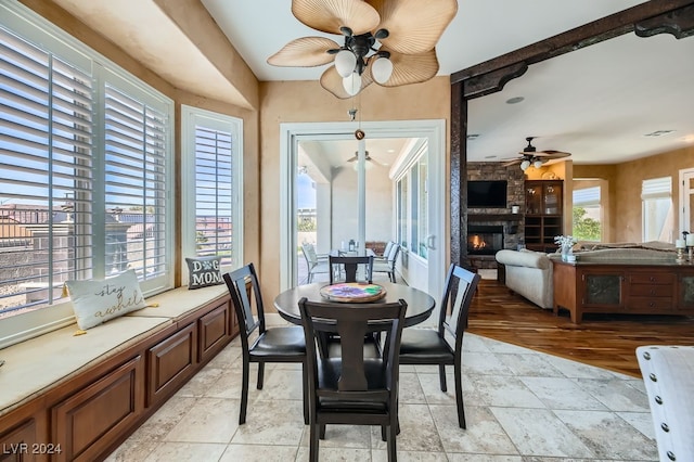 dining space with ceiling fan, light hardwood / wood-style floors, and a fireplace