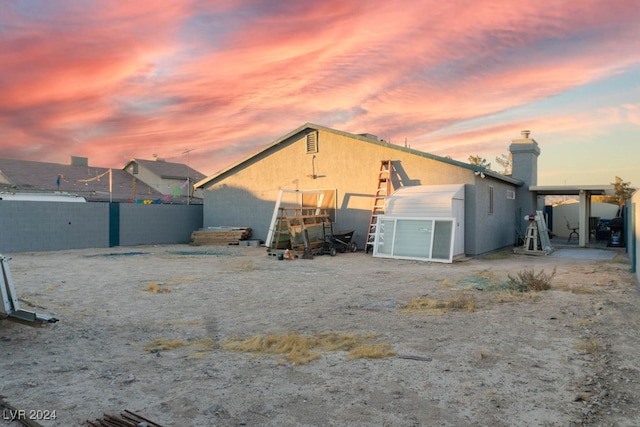 back house at dusk featuring an outbuilding