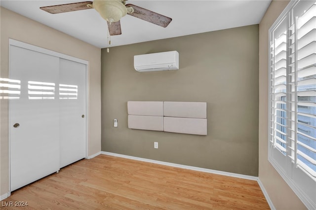 unfurnished bedroom with ceiling fan, a closet, light wood-type flooring, and a wall mounted AC