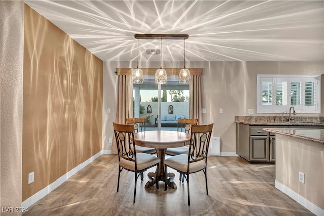 dining area featuring sink, lofted ceiling, and light wood-type flooring