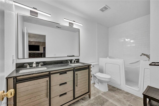 bathroom featuring a washtub, vanity, and toilet