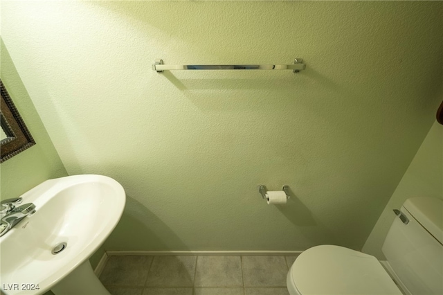 bathroom with toilet, tile patterned flooring, and sink