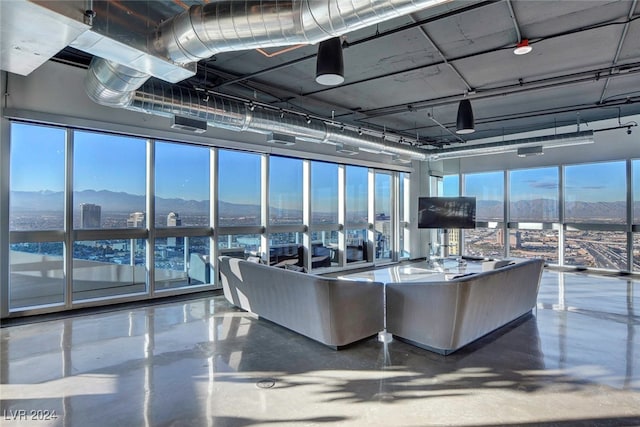 living room featuring concrete flooring, a mountain view, and a healthy amount of sunlight