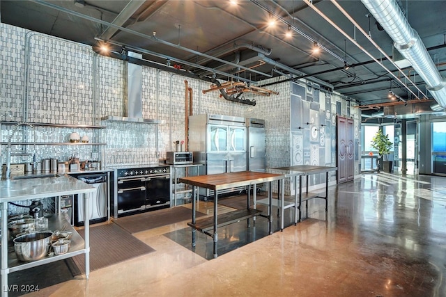 kitchen featuring a towering ceiling, appliances with stainless steel finishes, concrete floors, and exhaust hood