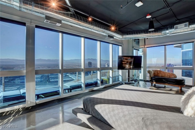 bedroom with concrete flooring, a mountain view, and multiple windows