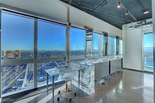 interior space with concrete floors, white cabinetry, a kitchen island, and plenty of natural light