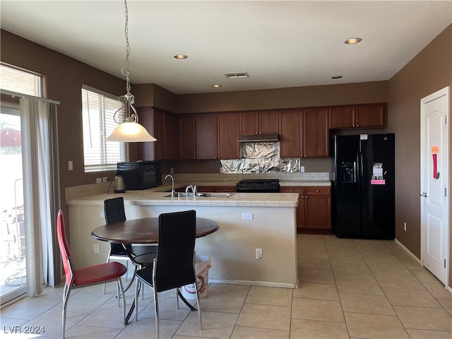 kitchen featuring kitchen peninsula, sink, black appliances, decorative light fixtures, and light tile patterned flooring