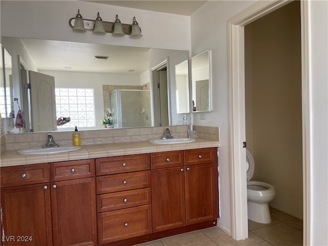 bathroom featuring vanity, toilet, walk in shower, and tile patterned flooring