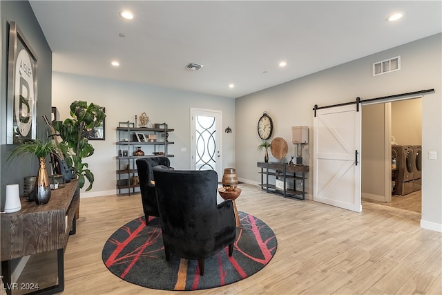 living room with a barn door, washer and dryer, and light hardwood / wood-style floors