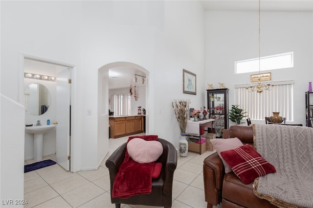 tiled living room with high vaulted ceiling, sink, and an inviting chandelier