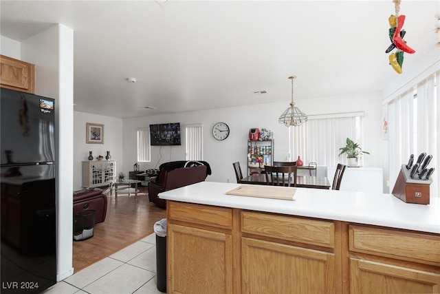 kitchen featuring light hardwood / wood-style flooring, black fridge, hanging light fixtures, and an inviting chandelier