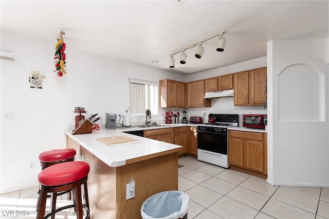 kitchen featuring sink, light tile patterned flooring, white range with gas cooktop, a breakfast bar area, and kitchen peninsula