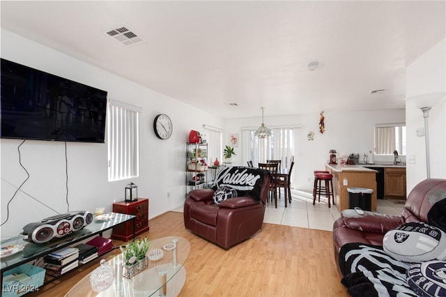 living room with a chandelier, light hardwood / wood-style flooring, and sink