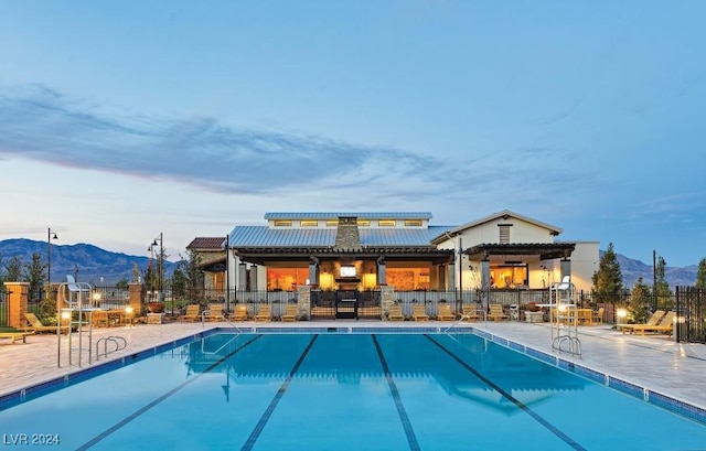 pool at dusk featuring a mountain view and a patio