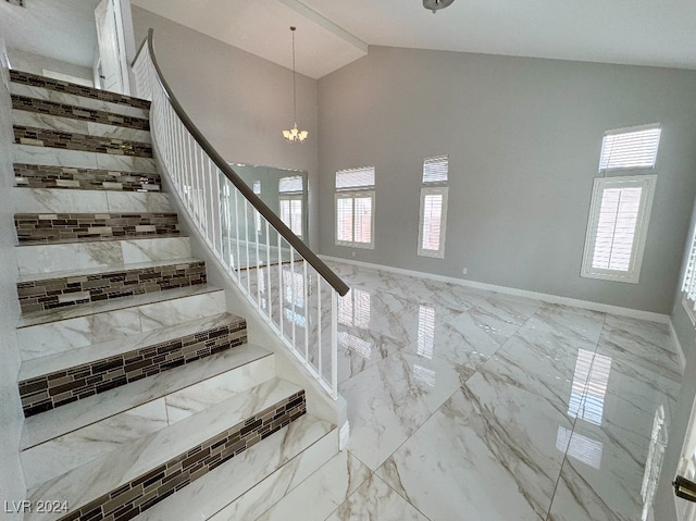 staircase with high vaulted ceiling and a notable chandelier