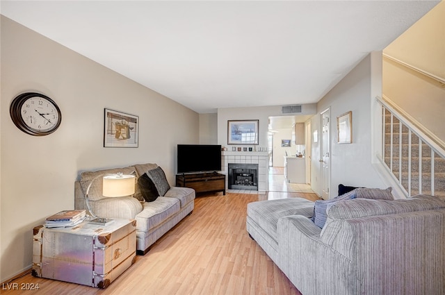 living room featuring a tile fireplace and light hardwood / wood-style floors