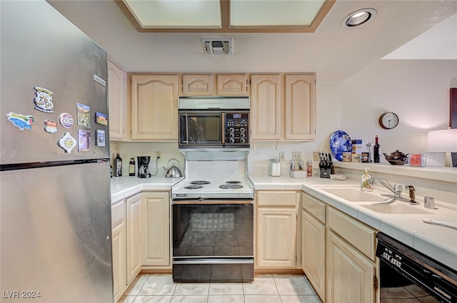 kitchen featuring light brown cabinetry, sink, black appliances, tile counters, and light tile patterned flooring