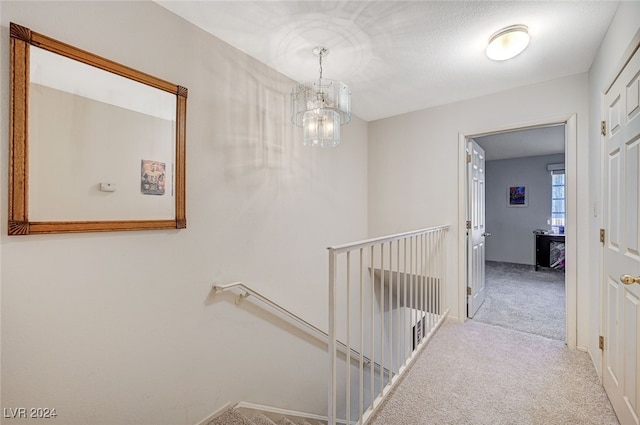 corridor featuring light carpet and an inviting chandelier