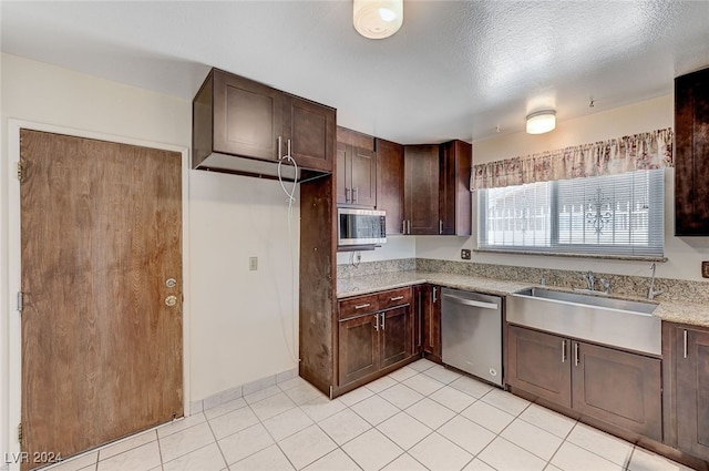 kitchen featuring light stone countertops, dark brown cabinets, a textured ceiling, and appliances with stainless steel finishes