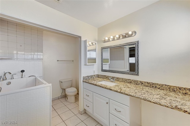 bathroom with tile patterned flooring, vanity, a relaxing tiled tub, and toilet