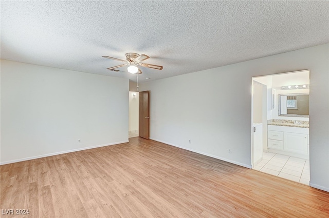 spare room featuring a textured ceiling, light hardwood / wood-style flooring, and ceiling fan