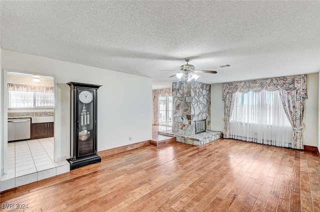 unfurnished living room featuring a textured ceiling, light hardwood / wood-style flooring, ceiling fan, and a healthy amount of sunlight