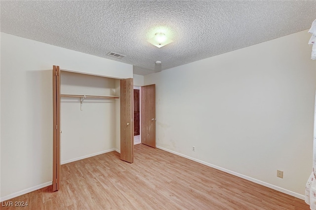 unfurnished bedroom with a closet, light hardwood / wood-style floors, and a textured ceiling