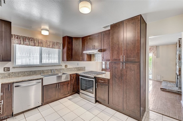 kitchen featuring sink, light tile patterned floors, a textured ceiling, and appliances with stainless steel finishes