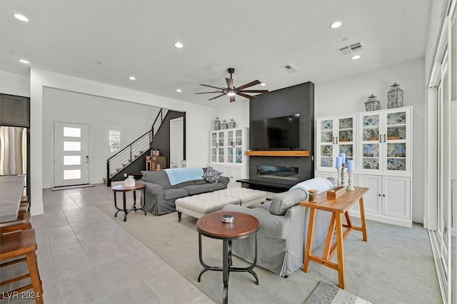 tiled living room featuring ceiling fan and a fireplace