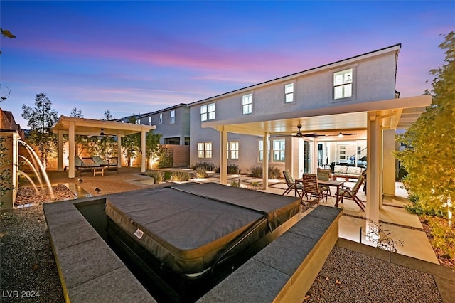 back house at dusk with ceiling fan and a patio