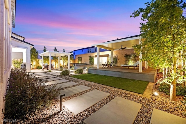 yard at dusk with a patio and ceiling fan