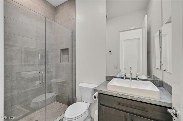 bathroom with vanity, toilet, and a shower with shower door