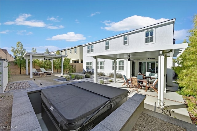 rear view of property with ceiling fan, a patio, and a hot tub