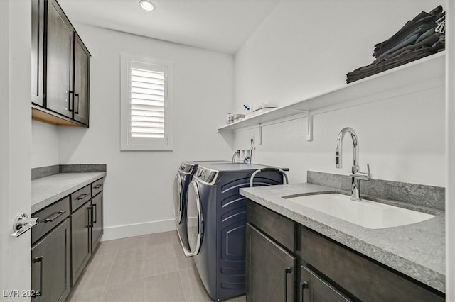 laundry area with washer and clothes dryer, light tile patterned floors, cabinets, and sink