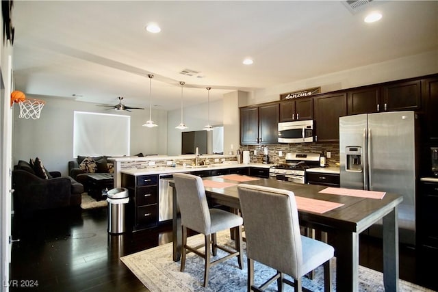 kitchen featuring pendant lighting, dark hardwood / wood-style floors, ceiling fan, decorative backsplash, and appliances with stainless steel finishes