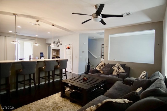 living room featuring ceiling fan with notable chandelier and dark wood-type flooring