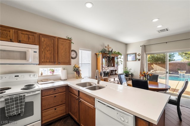 kitchen with kitchen peninsula, dark hardwood / wood-style flooring, white appliances, and sink