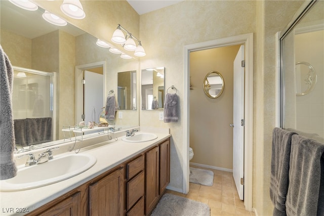 bathroom with tile patterned floors, vanity, a shower with shower door, and toilet