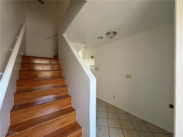 stairway featuring a textured ceiling and tile patterned floors