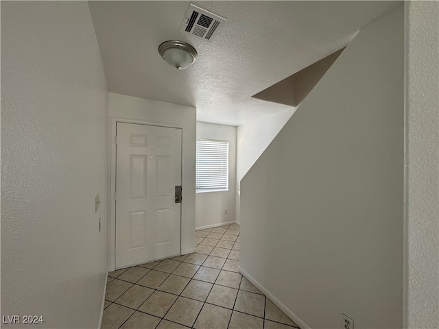 hall featuring light tile patterned floors and a textured ceiling