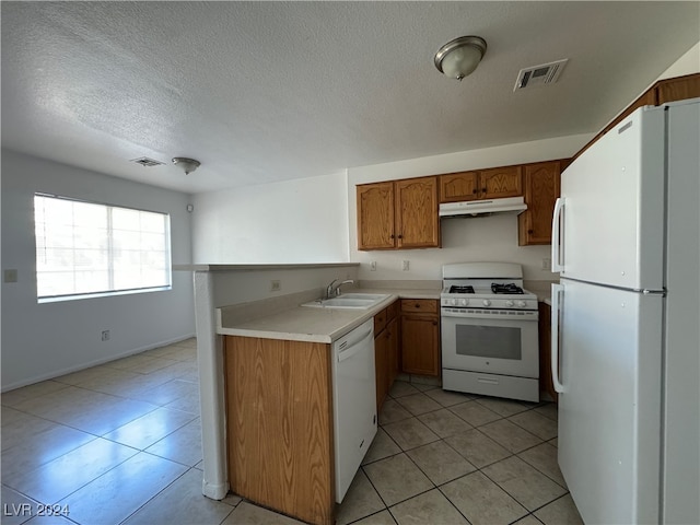 kitchen featuring light tile patterned flooring, a textured ceiling, white appliances, and sink