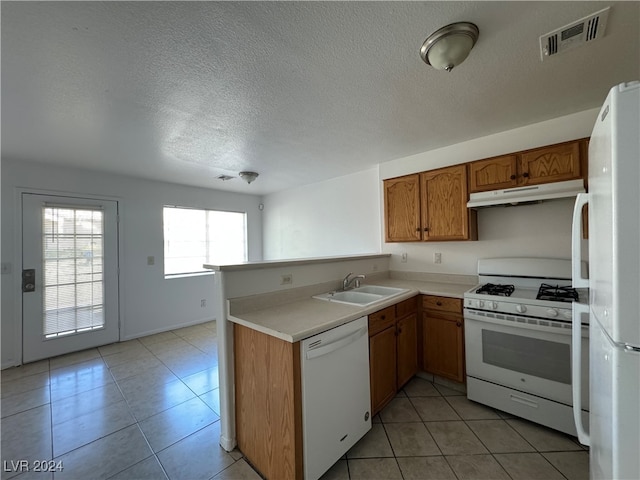 kitchen featuring sink, light tile patterned floors, white appliances, a textured ceiling, and kitchen peninsula