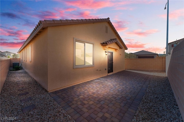 back house at dusk featuring a patio and cooling unit