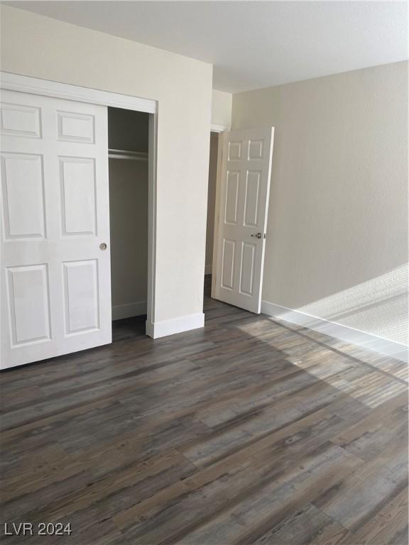 5317 Indian River Dr Unit 295, Las Vegas, NV 89103 - unfurnished bedroom with dark wood-style flooring, a closet, and baseboards