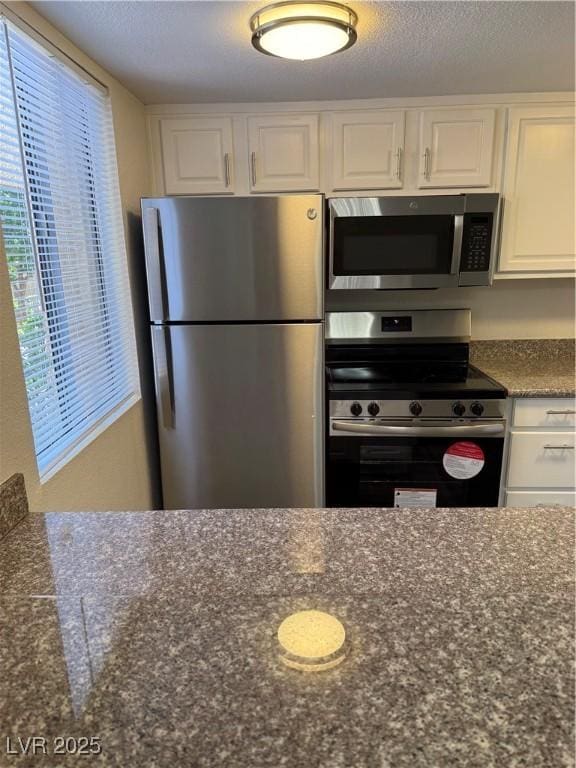 5317 Indian River Dr Unit 295, Las Vegas, NV 89103 - kitchen featuring stainless steel appliances, white cabinets, and dark stone counters