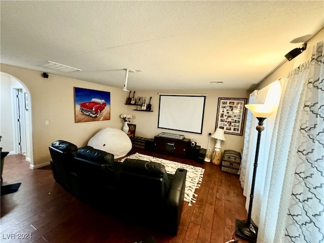 cinema room with dark wood-type flooring and a textured ceiling