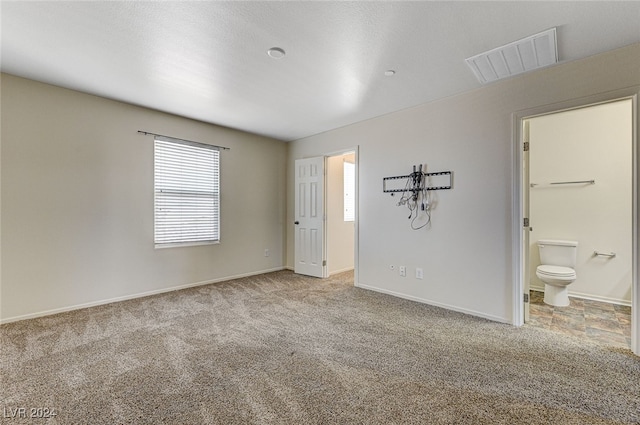 unfurnished bedroom featuring ensuite bathroom and light carpet