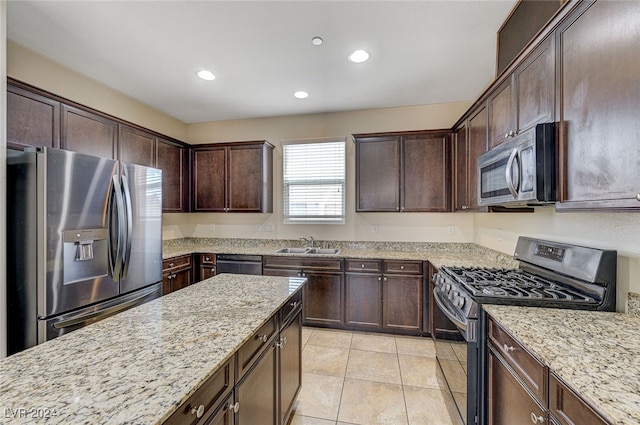 kitchen featuring dark brown cabinets, stainless steel appliances, light stone counters, and sink