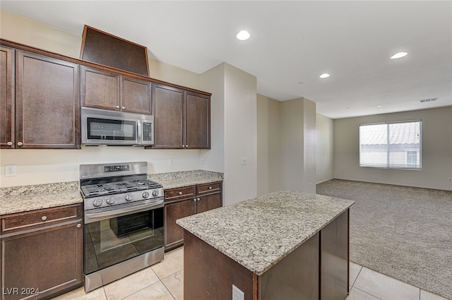 kitchen featuring a center island, light carpet, appliances with stainless steel finishes, light stone counters, and dark brown cabinetry