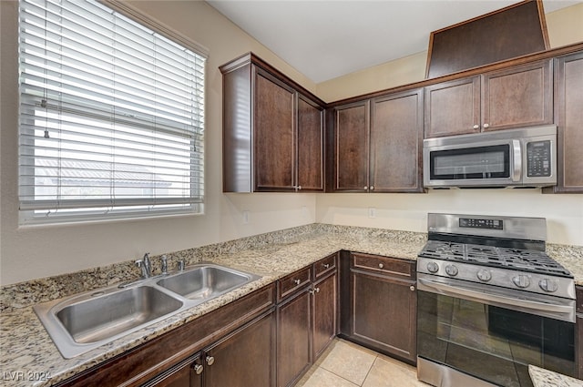 kitchen with light stone countertops, sink, stainless steel appliances, dark brown cabinets, and light tile patterned flooring